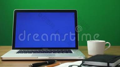 笔记本电脑，桌面上有绿色屏幕和黑色记事本。 绿色屏幕背景